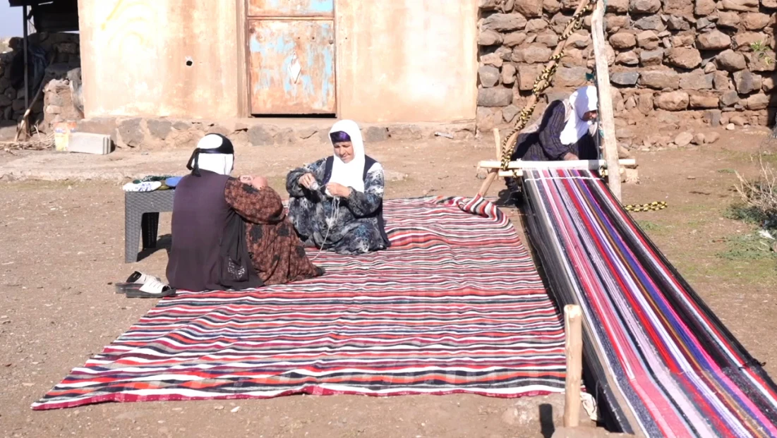 Evinin bahçesindeki tezgahta asırlık yöntemle kilim dokuyor