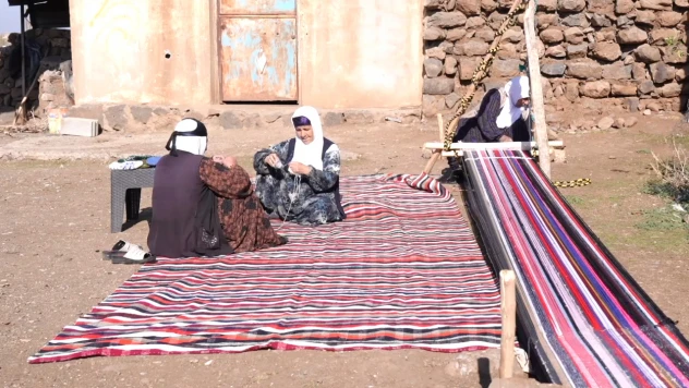 Evinin bahçesindeki tezgahta asırlık yöntemle kilim dokuyor