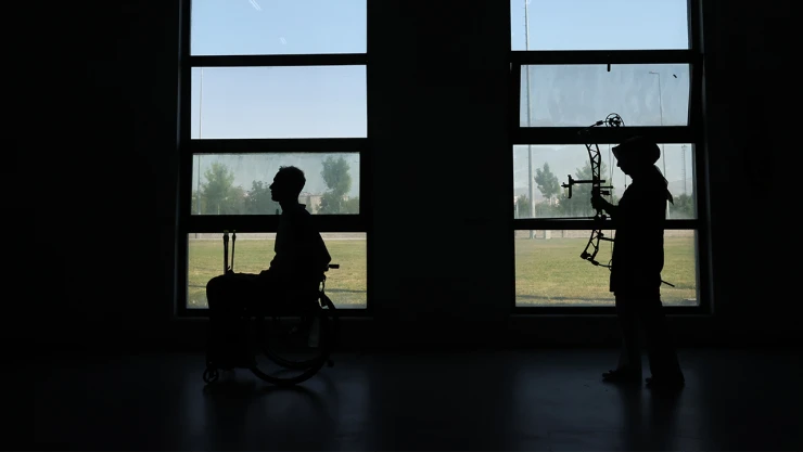 Felç kalan eşini tekerlekli sandalyeyle hedefe taşıyor